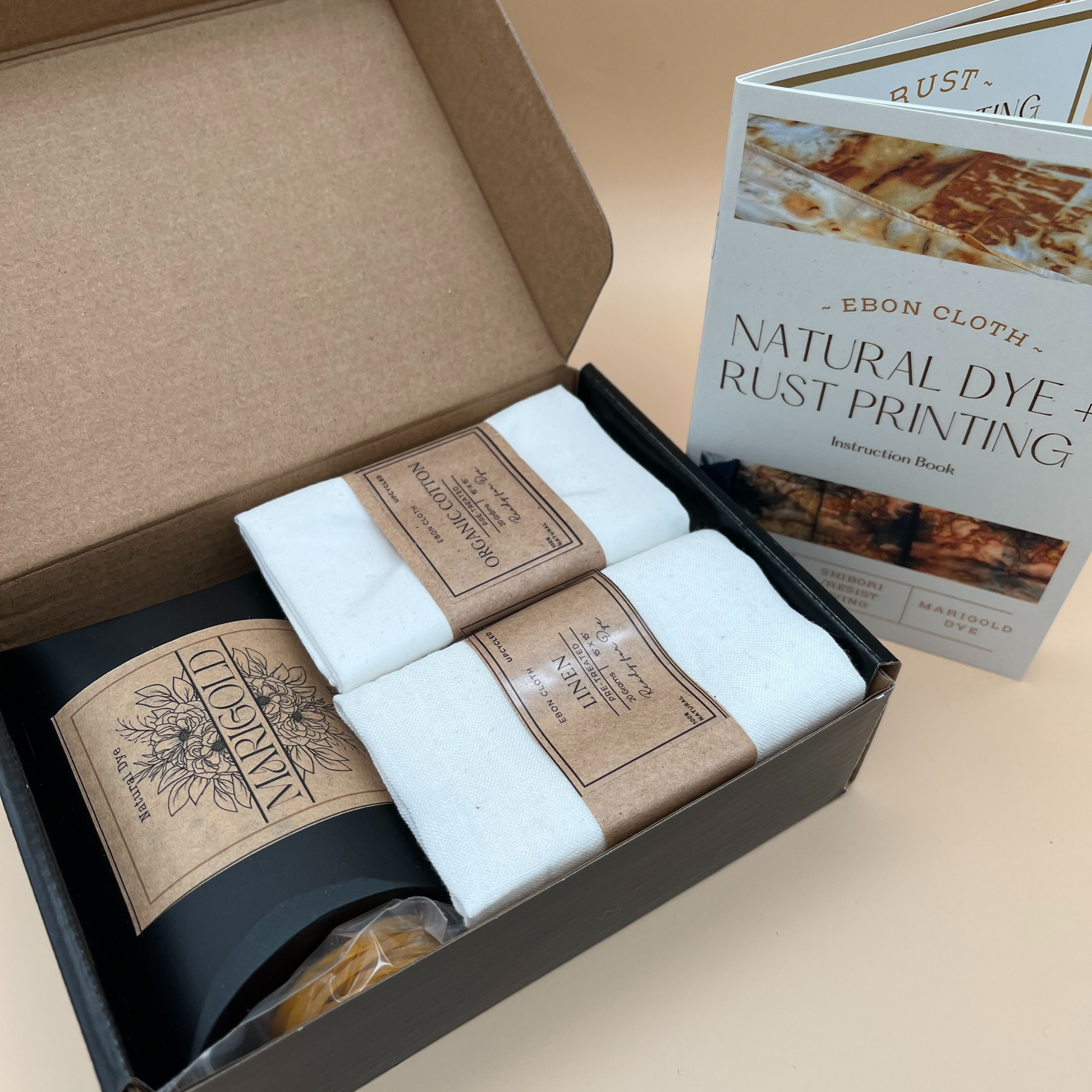 Complete natural dye textile kit in an eco-friendly box, includes undyed fabric, marigold dye, step-by-step instructional booklet, and resist dyeing tools—perfect for beginners and fibre artists exploring botanical fabric dyeing.